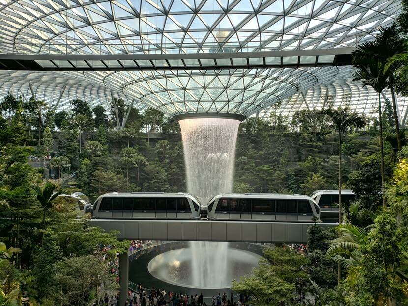 Foto van een futuristische stad met een binnentuin en een moderne passerende tram.